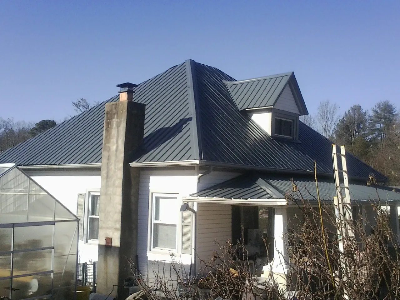 Dark blue standing seam metal roof on a white farmhouse with dormer — Slate & Tile Roof Repair by Roofing Brothers in Monrovia