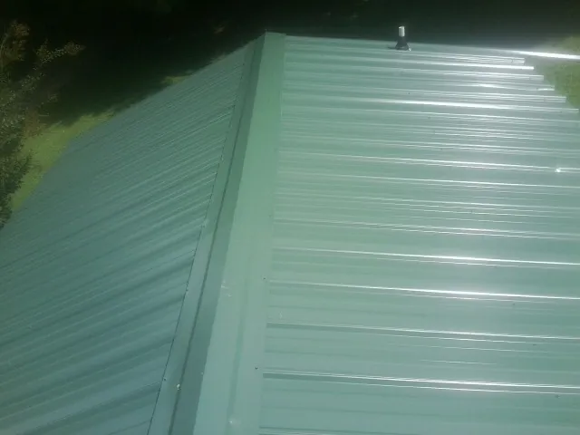 New green metal panels meeting at the ridge of a roof — Flat Roof Repair work by our crew in Monrovia
